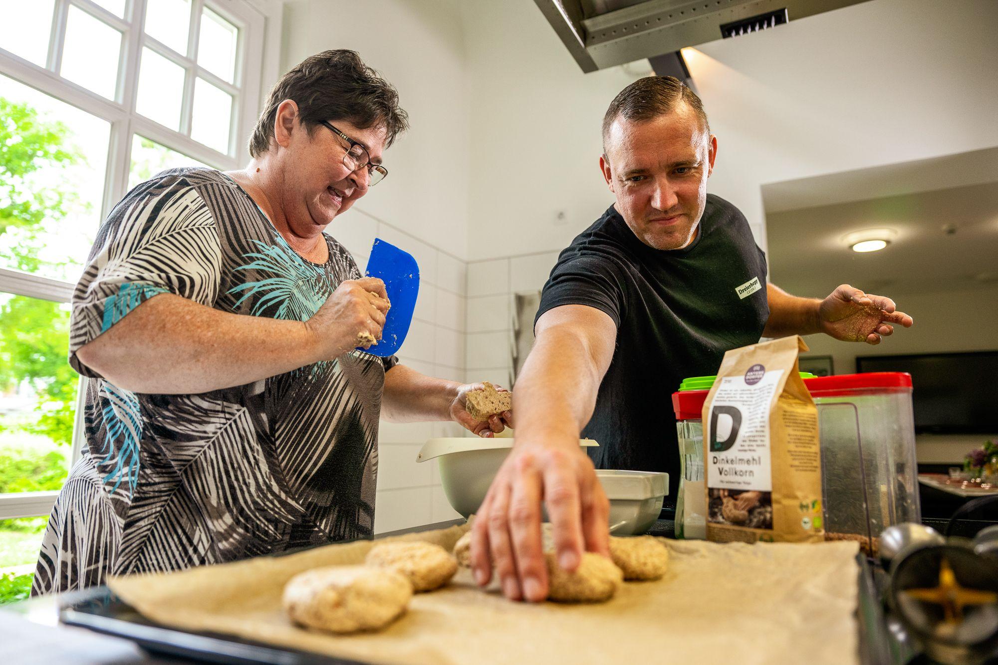 Ein Koch hilft einer Patientin in der Lehrküche
